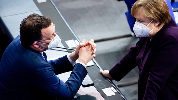 Bundesgesundheitsminister Jens Spahn und Bundeskanzlerin Angela Merkel mit FFP2-Masken sprechen im Bundestag. © dpa picture alliance Foto: Bernd von Jutrczenka