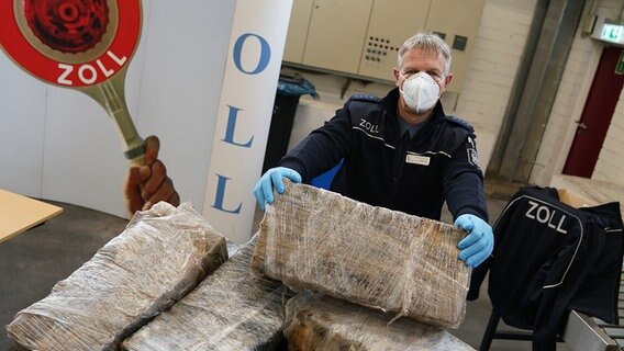 Andreas Franke, stellvertretender Pressesprecher des Zollfahndungsamtes Hamburg, präsentiert auf einem Medientermin im Hafen einen Teil des sichergestellten Kokains, das hinter Bananenpaletten versteckt war (2022). © picture alliance Foto: Marcus Brandt