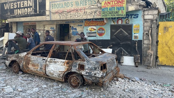 Junge Männer sitzen auf einem ausgebrannten Auto im Staddteil Carrefour-Feuilles, Port-au-Prince © ARD Foto: Anne Demmer