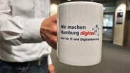 "Wir machen Hamburg digital" - Amt für IT und Digitalisierung" steht auf einem Kaffebecher. © NDR Foto: Christiane Zwick