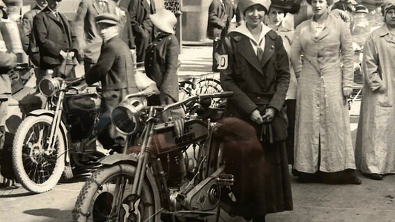 SW-Aufnahme einer historischen Harley Davidson, daneben eine Frau. © ARD Foto: Sebastian Hesse