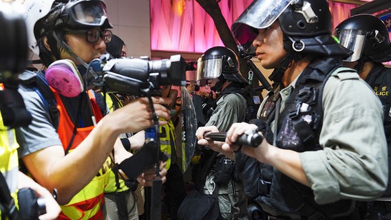 Ein Journalist und ein Polizist stehen sich bei einer Demonstration in Hongkong gegenüber. © dpa picture alliance Foto: Alex Hufford