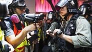 Ein Journalist und ein Polizist stehen sich bei einer Demonstration in Hongkong gegenüber. © dpa picture alliance Foto: Alex Hufford