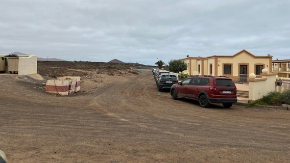 In einer kargen Landschaft stehen Autos vor einem flachen gelben Gebäude. © ARD Madrid Foto: Franka Welz