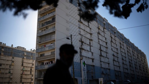 Ein nicht erkennbarer Mann vor einem Hochhaus in einer Marseiller Vorstadt-Hochhaussiedlung. © dpa picture alliance Foto: Daniel Cole