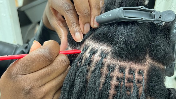 Microlocks (kleine Dreadlocks) werden an einem Kopf geflochten. © ARD Foto: Katrin Brand