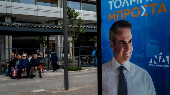 An einer Haltestelle ist ein Wahlkampfplakat mit einem Porträt des griechischen Ministerpräsidenten Mitsotakis zu sehen. © picture alliance Foto: Angelos Tzortzinis