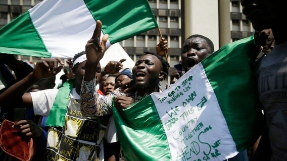 Demonstranten schwenken bei einem Protest gegen Polizeigewalt die nigerianische Fahne. © AP/dpa Bildfunk Foto: Sunday Alamba