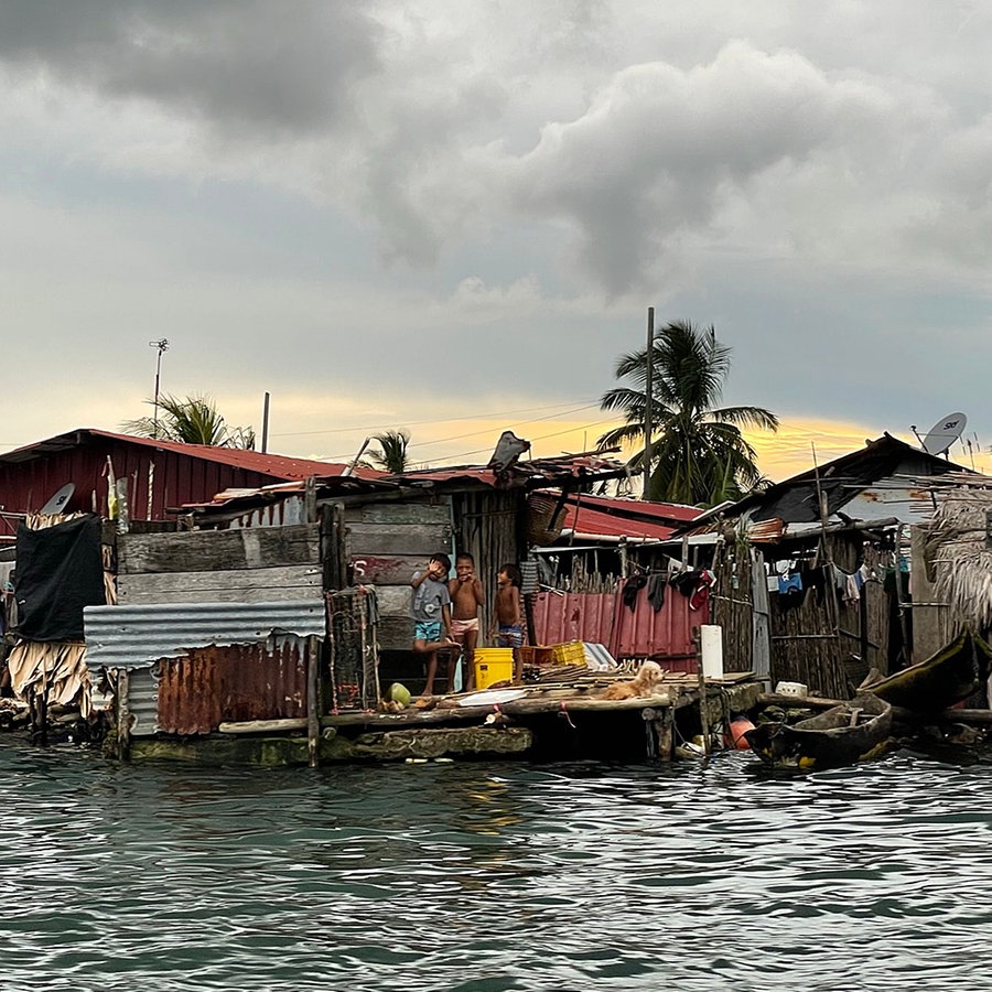 Einfache Häuser mit Wäscheleinen und Menschen unmittelbar am Meer. © ARD Foto: Anne Demmer