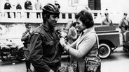 Eine Frau heftet am 25.04.1974 einem Soldaten in Lissabon, Portugal, eine rote Nelke an. Die rote Nelke ist das Symbol der portugiesischen Revolution. © Picture alliance Foto: Telimprensa