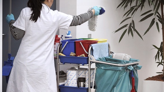 A cleaner with a cleaning trolley.  © picture alliance / SvenSimon |  FrankHörmann Photo: SvenSimon |  Frank Hormann