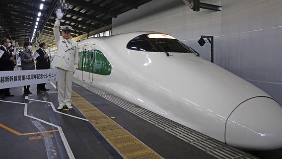 Ein Shinkansen (Zug) und ein Bahnmitarbeiter an der JR Niigata Bahnhofs-Station. © picture alliance / Kyodo 