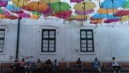 Blick auf einen Platz in Stadt Timisoara, über dem bunte Regenschirme aufgehängt sind. © picture alliance ZUMAPRESS Foto: Matias Basualdo