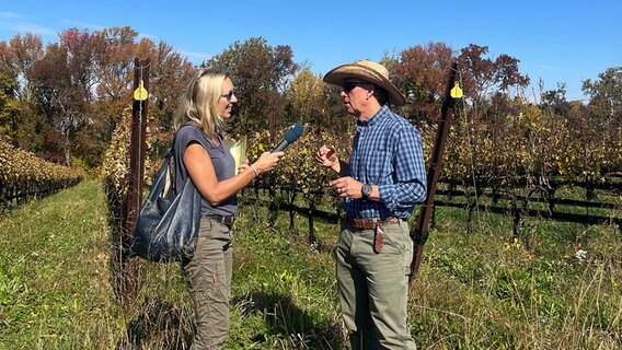 ARD-Korrespondentin Claudia Sarre interviewt den Winzer Tom Croghan an seinem Weinberg. © ARD 