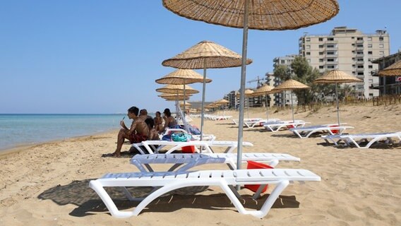 Einige Badegäste sitzen auf Liegen am Strand von Varosha. © dpa picture alliance Foto: Danil Shamkin