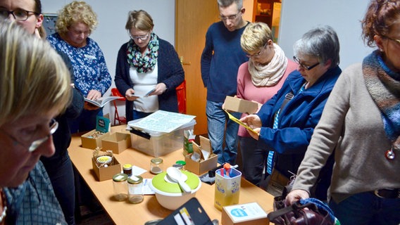 Teilnehmer am Plastikfrei-Stammtisch in der Nordheide werfen einen Blick auf die "Zutaten" für ein selbsthergestelltes Geschirrspülmittel. © NDR 