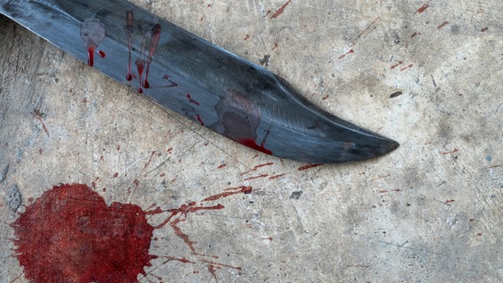 Blutige Messerspitze vor einem grauen Hintergrund. © Fotolia Foto: ratsadapong