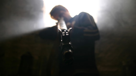 Eine Person zielt mit einer Waffe in Richtung Kamera. © photocase.de/Kallidri Foto: Kallidri