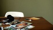 Auf einem Tisch liegen ein Kopfhörer und mehrere Fotografien. © complize / photocase.de Foto: complize