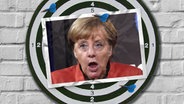 Eine Bildmontage zeigt eine Dartscheibe. Darauf ist eine Postkarte zu sehen, die Angela Merkel mit entsetzt aufgerissenem Mund zeigt. © imago images/ Belga Foto: imago images /Belga