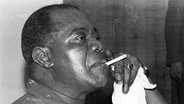 Der Jazz-Musiker Louis Armstrong raucht eine Zigarette, 1961  