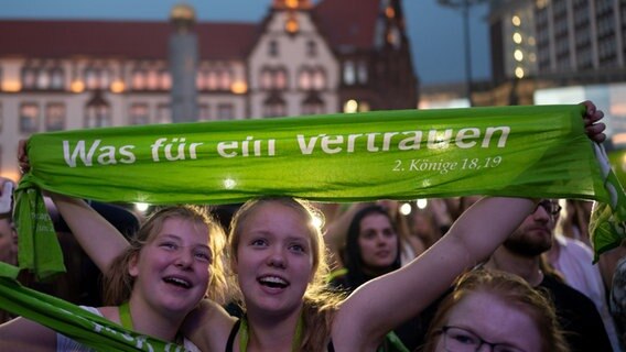 Besucherinnen des 37. Deutschen Evangelischen Kirchentages in Dortmund halten das Motto des Kirchentages auf einem Schal hoch: "Was für ein Vertrauen". Besucherinnen des 37. Deutschen Evangelischen Kirchentages in Dortmund halten das Motto des Kirchentages auf einem Schal hoch: "Was für ein Vertrauen". © picture alliance / dpa Foto: Bernd Thissen