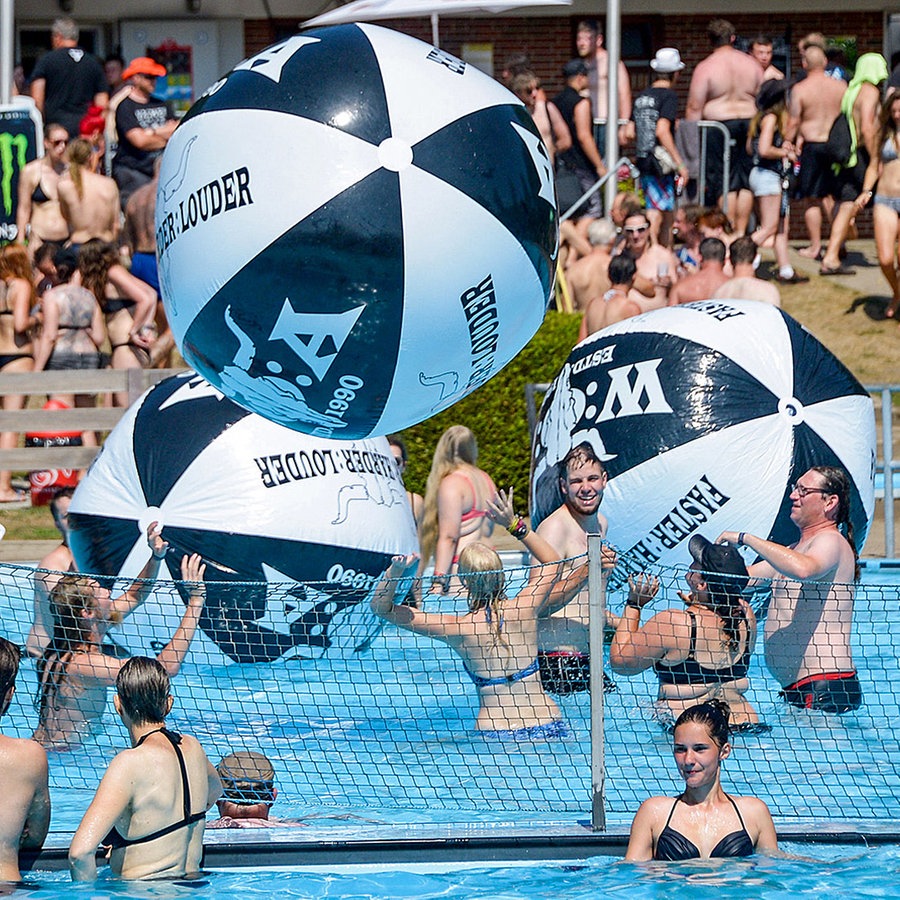 Badende werfen in einem Pool drei riesige aufblasbare Bälle hin und her. © dpa-Bildfunk Foto: Axel Heimken