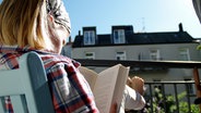 Ein Kind sitzt auf dem Balkon und liest ein Buch. © NDR Foto: Katharina Mahrenholtz