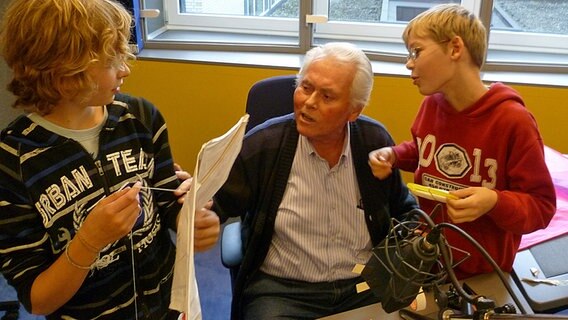 Zwei Kinder und ein älterer Herr basteln in einem Hörfunkstudio Drachen selber. © NDR Foto: Jürgen Kopp