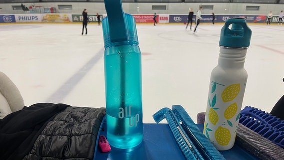 Trinkflaschen stehen am Rand einer Eisbahn. © NDR Mikado Foto: Ines Kaffka