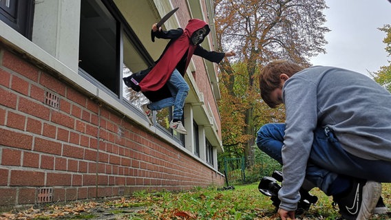 Ein Kind mit einer Kamera filmt einen Schauspieler vom Boden aus. © NDR Mikado Foto: Christian Schepsmeier