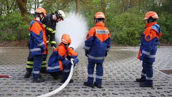 Kinder von der Jugendfeuerwehr testen einen Wasserschlauch. © NDR Mikado Foto: Fatma Sahin