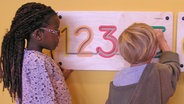 Ein Mädchen und ein Junge in der Ausstellung "Zahlenreise - Mathe macht Spaß" im Altonaer Museum.  