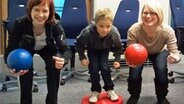 Zwei junge Frauen und ein Junge machen in einem Hörfunkstudio eine Skigymnastikübung. © NDR 