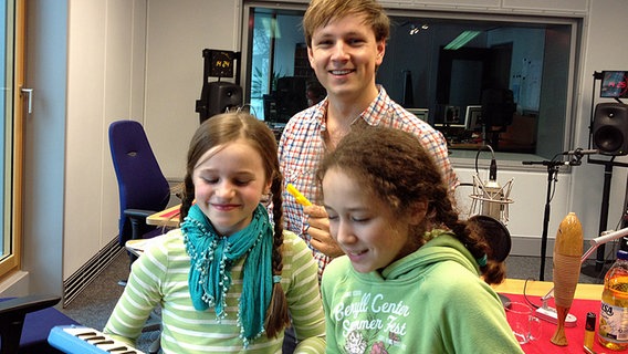Zwei Mädchen mit einer Melodika und ein junger Mann mit Kazoo in einem Hörfunkstudio. © NDR Foto: Svenja Müller