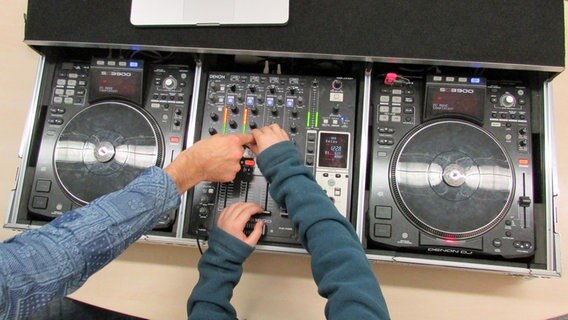 Die Arme eines Kindes und einen Mannes bedienen die Regler eines DJ-Mischpultes. © NDR Foto: Lenne Kaffka