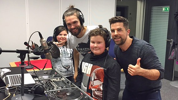 Zwei Kinder und zwei Männer stehen an einem DJ-Pult im Radiostudio. © NDR Foto: Svenja Müller