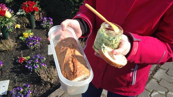 Ein Kind hält eine Plastikbox mit Baguette und ein Glas mit Bärlauchbutter in der Hand. © NDR Foto: Beke Schulmann