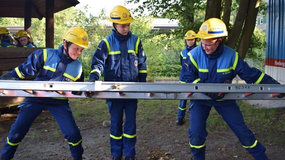 Drei Kinder in THW-Uniformen bauen eine Steckleiter zusammen. © NDR Foto: Lenne Kaffka