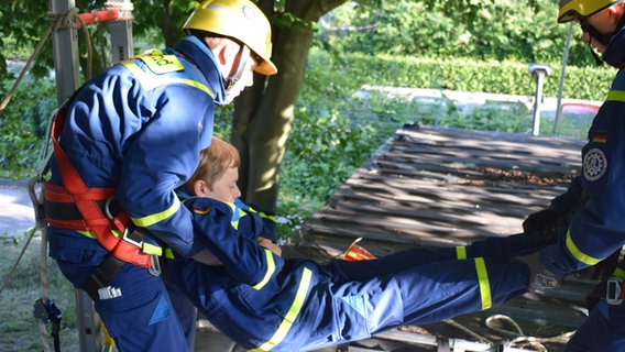 Bei einer Übung des THW wird ein Kind von Helfern auf eine Liege gelegt. © NDR Foto: Lenne Kaffka