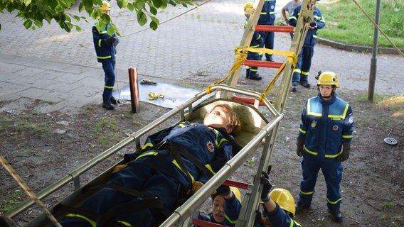 Bei einer Übung des THW wird ein Kind auf einer Liege über eine Leiter geborgen. © NDR Foto: Lenne Kaffka