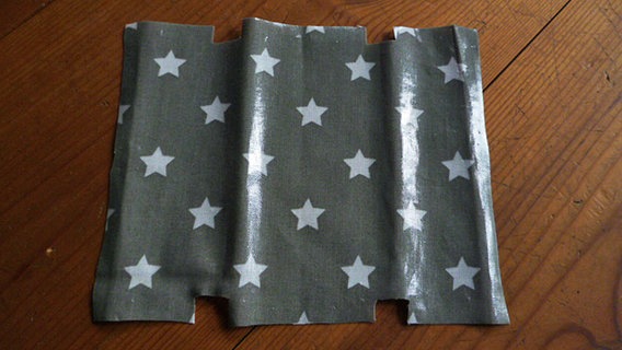 Nach dem Schnittmuster für eine selbstgemachte Tasche ausgeschnittener Wachsstoff in der Farbe grau mit weißen Sternchen. © NDR Foto: Elena Perez