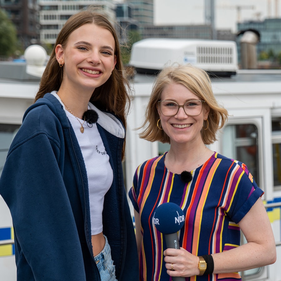 Das ehemalige Pfefferkorn Alice (Emilia Flint) mit NDR Moderatorin Jessica Schlage Emilia Flint und Jessica Schlage stehen im Hafen vor einem Boot der Wasserschutzpolizei. © NDR Foto: Aaron Moser