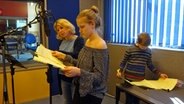 Eine Frau und zwei Kinder sprechen Texte in Mikrofone. © NDR 