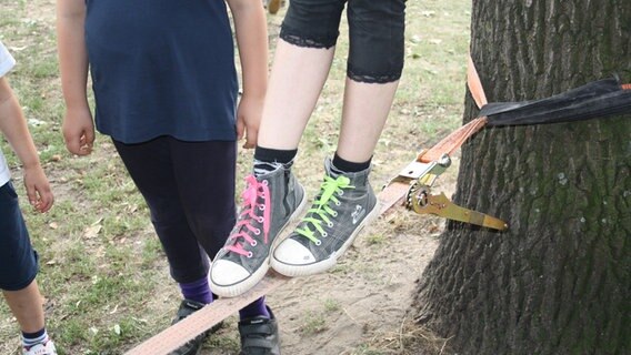 Zwei Kinderfüße in Turnschuhen balancieren auf einer Slackline. © NDR Foto: Beke Schulmann