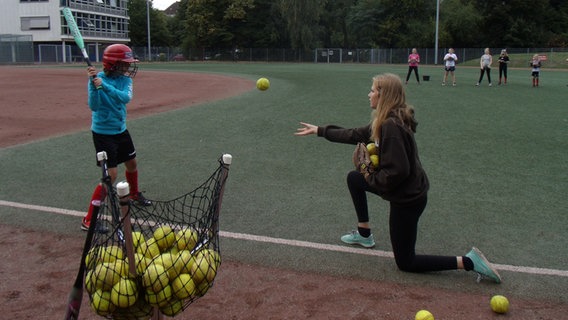 Trainerin Antonia wirft einer Spielerin ihrer Softball-Mädchenmannschaft der "Hamburg Knights" einen Ball zu. © NDR Foto: Beke Schulmann