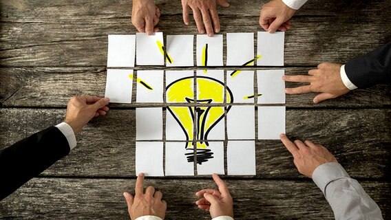 Hände fügen Puzzleteile einer leuchtenden Glühbirne zusammen. © fotolia Foto: Gajus