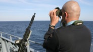 Ein Soldat der Bundesmarine blickt an Bord der Fregatte "Brandenburg" durch ein Fernglas auf das Meer. © dpa-Bildfunk 
