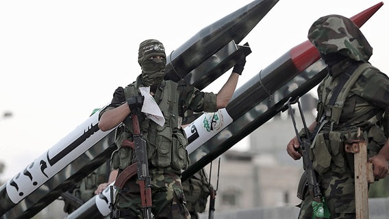 Zwei bewaffnete maskierte Palästinenser postieren sich vor zwei Kurzstreckenraketen. © dpa bildfunk Foto: Mohammed Saber