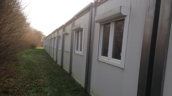 Wohncontainer für Geflüchtete stehen in einer Reihe auf einem freien Feld. © NDR Foto: Katharina Kaufmann